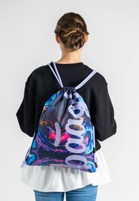 Schnürr-Rucksack in einem lebhaften, abstrakten Muster. Verfügt über lilafarbene Schriftzüge und verstellbare Träger, aus strapazierfähigem Stoff gefertigt.