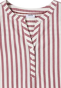 Chemise blanche avec des rayures rouges verticales, encolure ronde et quatre boutons blancs sur la patte de devant, l’étiquette indique "Cecil."