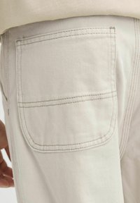 Heledad heled denimpüksid tagataskuga. Kangas on peene tekstuuriga mustriga, viimistletud toniseeriva tikandiga vastupidavuse tagamiseks.