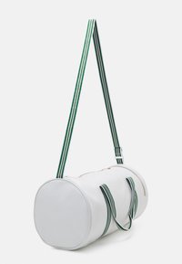 Borsa duffel cilindrica bianca realizzata in materiale liscio, con manici a strisce verdi e bianche e una chiusura con zip.