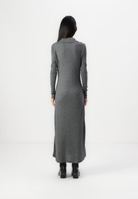 Long-sleeve, gray dress with a collar and fitted silhouette, made of soft fabric, reaching mid-calf. Paired with black heeled boots.