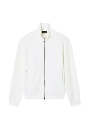 Weiße Jacke mit Reißverschluss, Stehkragen und Seitentaschen, flach auf weißem Hintergrund dargestellt.