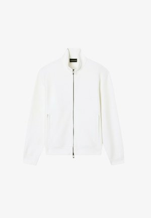 Chaqueta blanca con cremallera, cuello alzado y bolsillos laterales, mostrada extendida sobre un fondo blanco.
