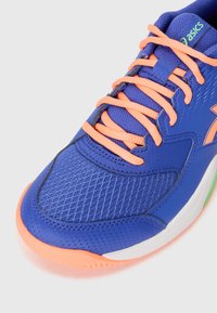 Blå sportsko med mesh-overdel, oransje snøringer og hvit såle. Har teksturerte mønstre og et distinkt Asics-logo i grønt.