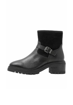 Botte noire mi-mollet en cuir et daim avec un talon épais, une semelle à gros crampons et une bride décorative avec boucle latérale.