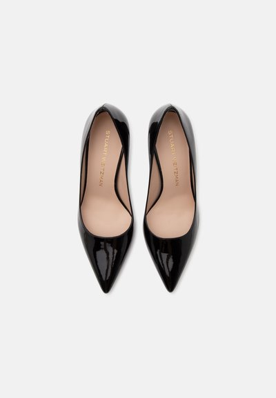 Paire d'escarpins noirs en cuir verni à bout pointu avec semelles intérieures beiges et marquage "Stuart Weitzman" à l'intérieur sur un fond clair.