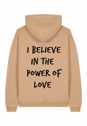 Felpa beige con cappuccio regolabile e polsini a costine. Presenta un testo frontale che recita "CREDO NELL'ENERGIA DELL'AMORE" in carattere nero in grassetto.