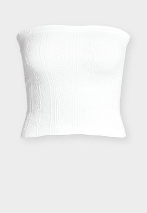 Haut tube blanc sans bretelles en maille avec motifs floraux et texturés, silhouette ajustée.