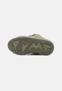 Σόλα παπουτσιού με υφή και γεωμετρικό σχέδιο σε ανοιχτό πράσινο και γκρι, περιλαμβάνοντας κυκλικά κράτη και γωνιακά στοιχεία για πρόσφυση.