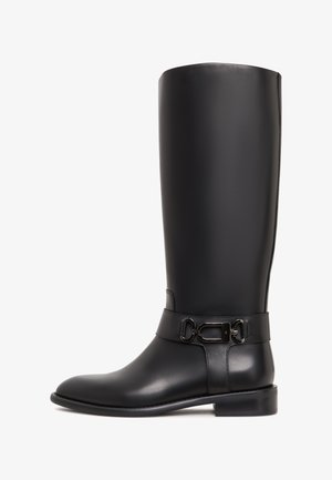 Zwarte leren kniehoog laars met een gladde textuur, ronde neus en een decoratieve enkelgesp. Platte zool en minimalistisch ontwerp.