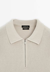 Jasnoszary bawełniany sweter z półzamkowym kołnierzem, prążkowaną fakturą oraz metką z napisem „Massimo Dutti” umieszczoną wewnątrz kołnierza.