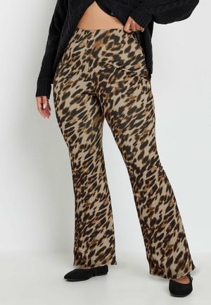 Luipaardprint uitlopende broek in bruin- en zwarttinten, gemaakt van een gladde stof. Gecombineerd met een zwarte textuurtrui en zwarte ballerina's.