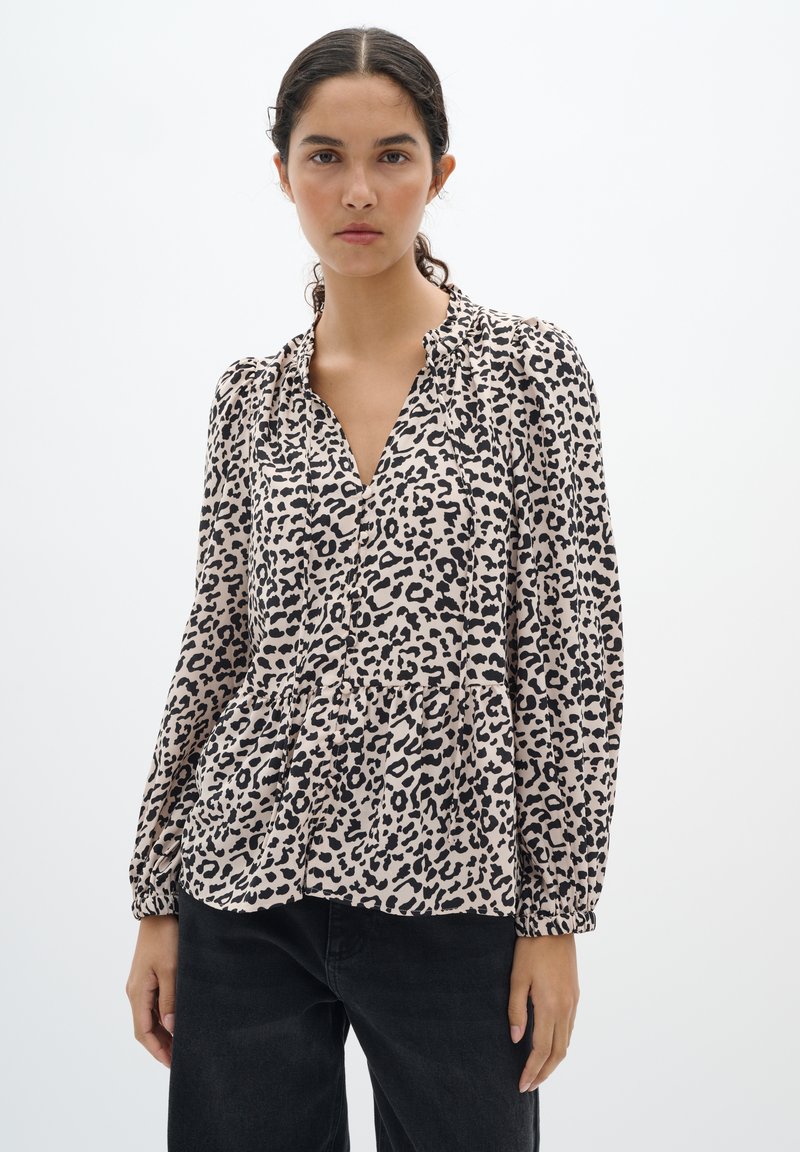 Bluse aus leicht beigem Stoff mit schwarzem Leopardenmuster, verfügt über einen V-Ausschnitt, geraffte Schultern und lange Puffärmel, mit einem lässigen Schnitt.