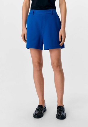 Blå shorts i skräddarsydd design, tillverkade av ett mjukt tyg. Har en platt midja, sidofickor och en rak skärning som slutar ovanför knät.