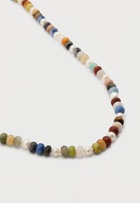 Κολιέ φτιαγμένο από μικρές στρογγυλές πολύχρωμες χάντρες και λευκές πέρλες τοποθετημένες σε εναλλασσόμε νο μοτίβο σε λευκό φόντο.