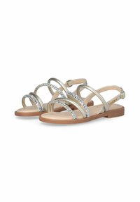 Sandalias metálicas plateadas con múltiples correas delgadas y detalles de strass. Diseñadas con una suela plana y una correa para el tobillo ajustable.