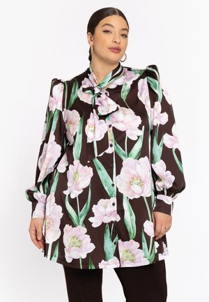 Blouse marron avec un grand motif floral rose, col à nœud, design boutonné, manches longues avec poignets froncés, texture de tissu lisse.