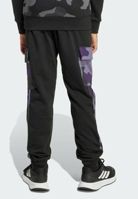 Black cargo pants with purple camouflage accents, featuring side pockets and elastic cuffs. Made from soft, flexible fabric.