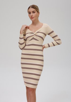 Robe en maille avec une silhouette ajustée, mettant en avant des rayures horizontales crème et marron, un détail noué au niveau du col, et des manches longues.