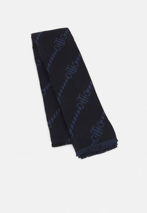 Ciemnoniebieski szalik z subtelnym diagonalnym wzorem logo i frędzlami na końcach, starannie złożony na jednolitym jasnym tle.