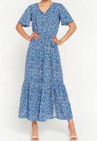 Modrá maxi šaty se vzorem, krátkými rukávy, výstřihem do V a vrstveným spodním lemem. Obsahují složité vzory v různých odstínech modré.