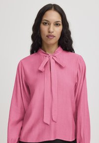 Blusa rosa con colletto e dettagli di cravatta, maniche lunghe e tessuto strutturato. Design semplice con una vestibilità rilassata e una caduta morbida.