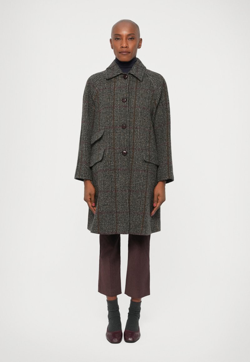 Grå houndstooth frakke med krave, tre knapper og sidelommer, parret med lilla cropped bukser, grå strømper og bordeaux sko.