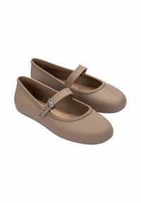Bailarinas marrones hechas de material suave, con punta redondeada y una tira delgada con un acento metálico a lo largo del empeine.