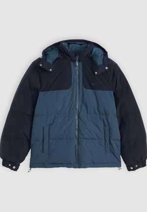 Puffer jacket with a dual-tone design in dark and light blue, featuring a zip front, hood, and side pockets. Made from textured fabric.