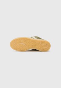 Sole di sneaker verde scamosciato con un motivo a spina di pesce testurizzato e una suola in gomma naturale. Strisce bianche lungo il lato.