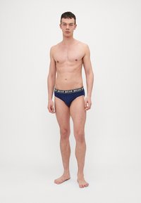 Mornarske modre kratke hlačke iz mehke tkanine s kontrastnim črnim pasom, na katerem je v beli barvi napis "justcavalli".