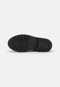 Suela de zapato de goma negra con profundas huellas, patrones de estrellas en la parte delantera y la marca "Liu Jo 37" visible sobre un fondo blanco.