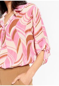 Mönstrad blus i rosa, brunt och krämfärgat med krage och uppvikta ärmar som har knappdetaljer. Slätt, lätt tyg med vågmönster.