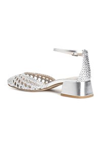 Sandalo con tacco argento e tomaia intrecciata, con punta chiusa e cinturino alla caviglia. Tacco basso a blocco e finiture metalliche lisce.