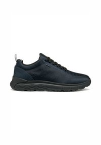 Zapatillas deportivas negras con una parte superior de malla texturizada, cuello acolchado y una suela de goma flexible con patrones en forma de ola. Los cordones son negros.