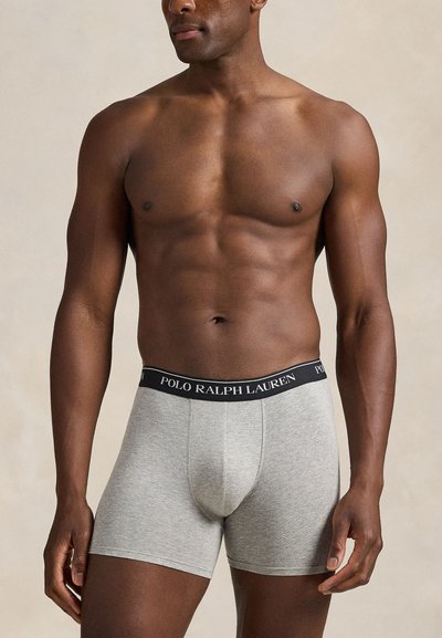 Grå bomullsboxershorts med svart midjeband där "POLO RALPH LAUREN"-logotypen syns. De har en åtsittande passform och når mitten av låret.