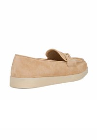 Suede slip-on shoes in tan, featuring a flat sole with a slightly raised back. The design includes a folded tongue detail and minimal stitching.