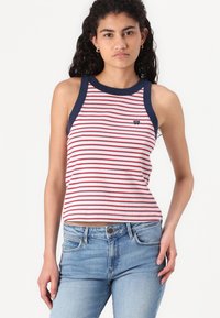 Débardeur rayé avec des rayures horizontales rouges et blanches, emmanchures et col contrastants en bleu marine, avec un petit logo sur le devant.