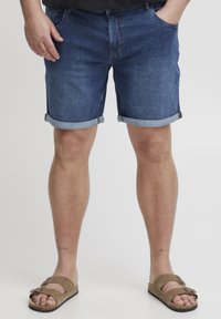 Mörkblå denimshorts med uppvikta ben, med en klassisk femficksdesign. I kombination med bruna sandaler med justerbara remmar.