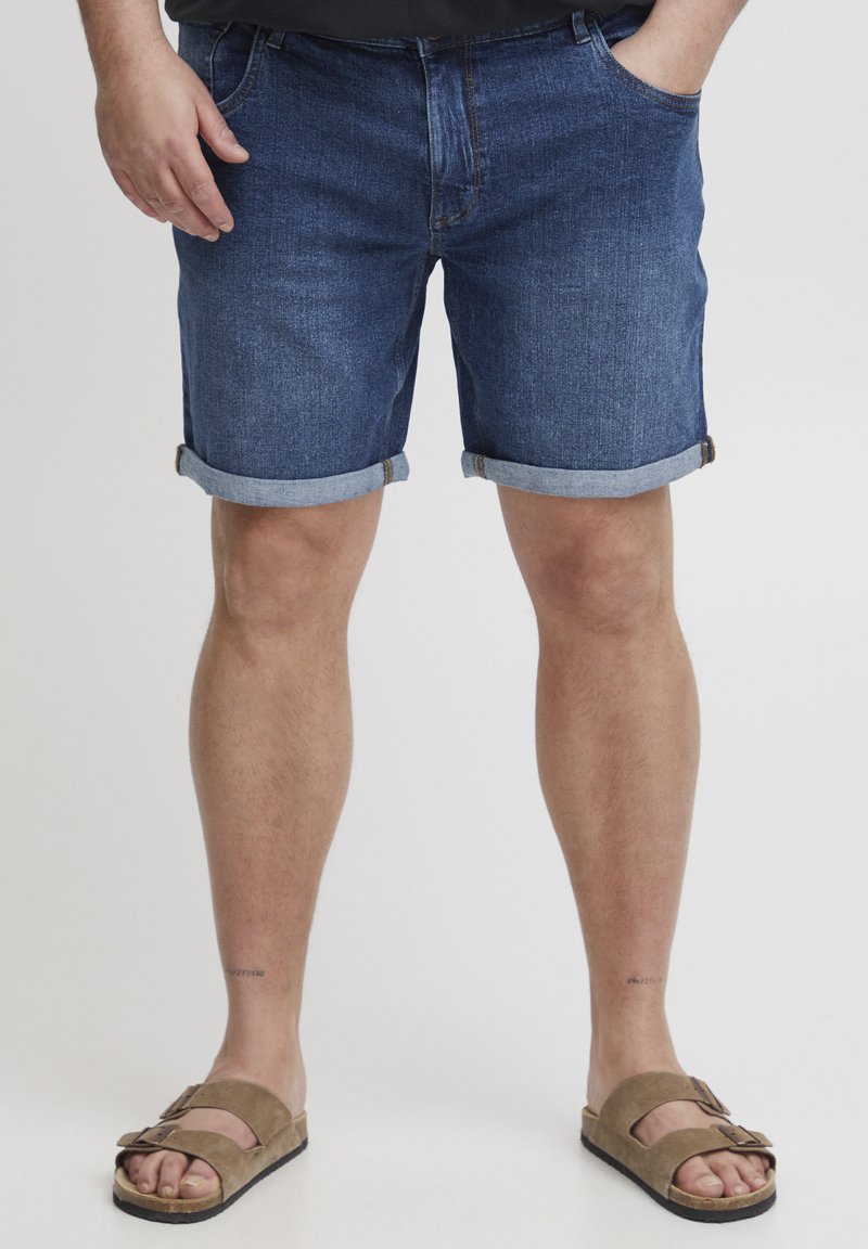 Mörkblå denimshorts med uppvikta ben, med en klassisk femficksdesign. I kombination med bruna sandaler med justerbara remmar.
