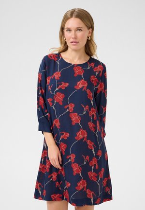 Vestido azul marino con estampado floral rojo, escote redondo y mangas tres cuartos. Tejido ligero y fluido con un corte relajado.