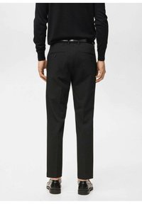 Czarne spodnie z prostymi nogawkami, wyposażone w dwie tylne kieszenie i gładką fakturę, w połączeniu z czarnymi butami i dopasowanym czarnym swetrem.