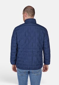 Giacca smanicata azul navy con colletto alto e texture trapuntata. Presenta maniche lunghe e una vestibilità comoda, adatta per un look casual.