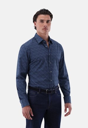 Blaue gemusterte Hemd mit Knopfleiste, langen Ärmeln und klassischem Kragen, kombiniert mit dunklen Denim-Jeans und einem schwarzen Gürtel.