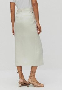 Svetle béžová sukně ke kolenům vyrobená z hladkého tkaného materiálu s přiléhavým pasem, decentními zadními kapsami a elegantním siluetou.