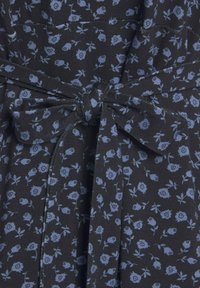 Schwarzes Kleid aus Stoff mit einem floralen Muster in Hellblau. Verfügt über ein gebundenes Taillendetail und eine subtile Textur.