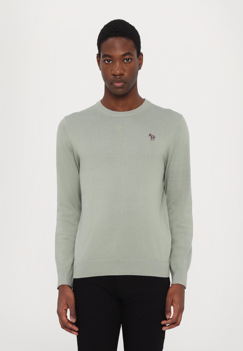 Suéter de malha verde claro com um decote redondo. Apresenta um pequeno logotipo bordado no peito. Punhos e cós ajustados.