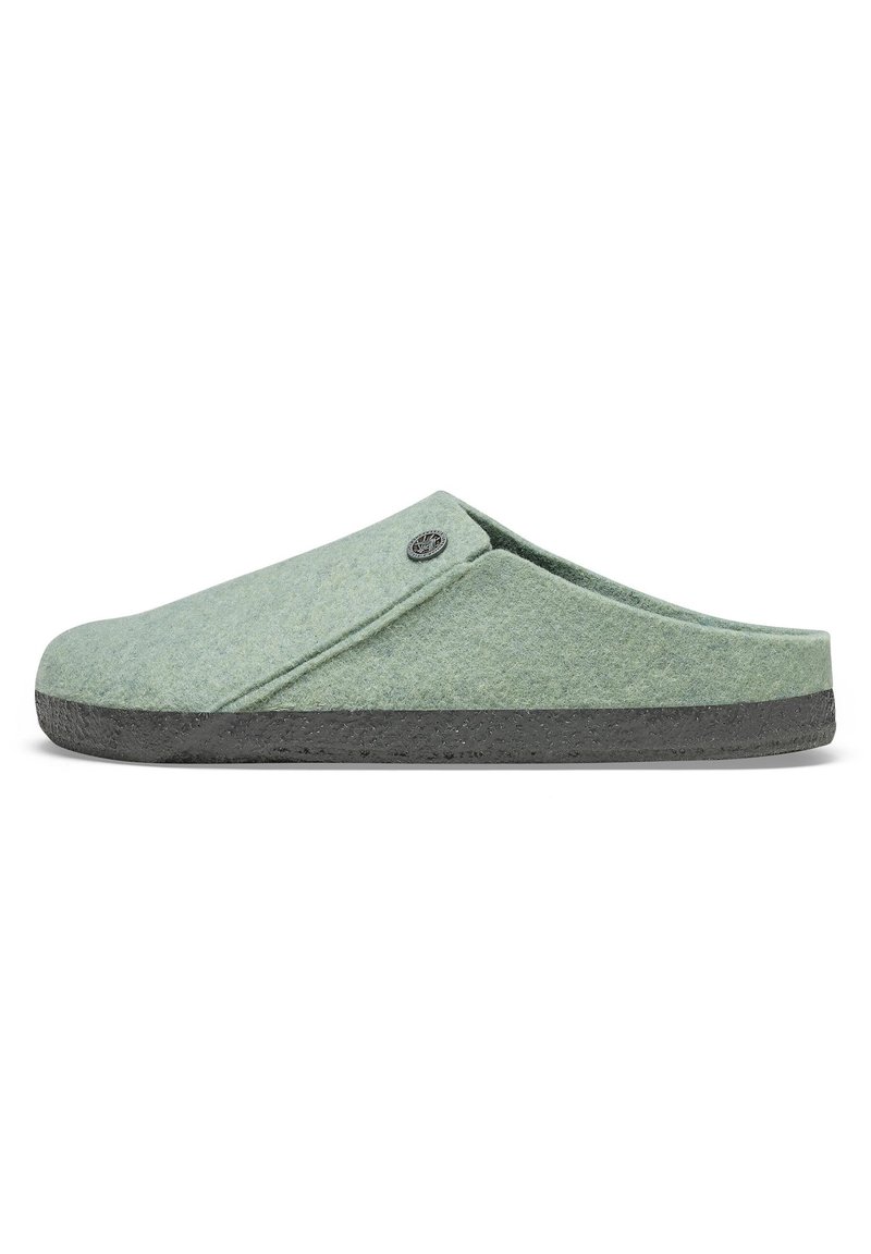 Grüne Filz-Schlüpfschuhe mit runder Zehenpartie, ausgestattet mit einer dunkelgrauen Gummisohle und einem kleinen runden Logo-Akzent auf dem Obermaterial.