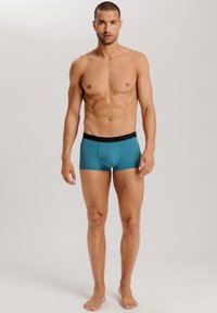 Herrens kalsonger i teal med svart midjeband. Har en snug passform och slät yta, designade för komfort och stöd.