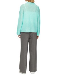 Pull en tricot bleu clair avec des manches longues et une coupe détendue, associé à un pantalon large gris et des baskets blanches.